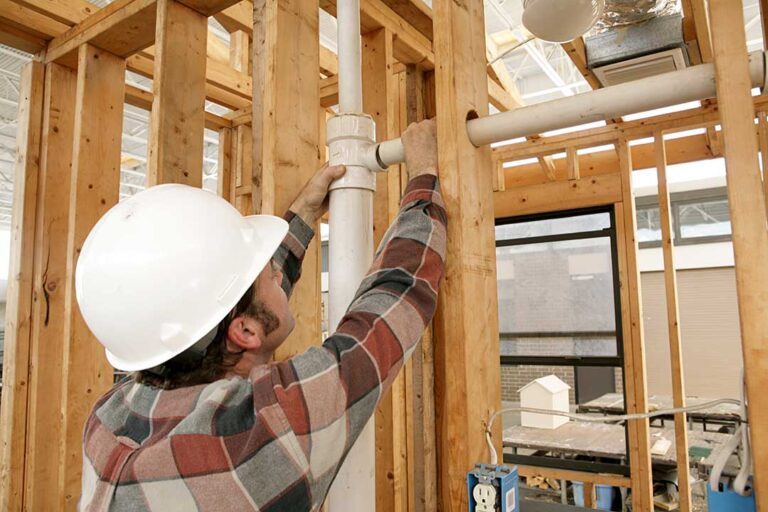 A person adjusting the settings on a wall-mounted tankless water heater in a residential utility room.